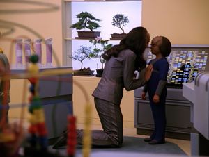 In the Enterprise day care centre, a talk Klingon woman with long dark hair is kneeling down to say goodbye to her son, a little Klingon boy. Her face is close to his, and she has her hand on his chest.  She's saying goodbye.