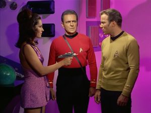 Luma points a gun at Kirk, while Scotty looks on gormlessly.