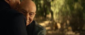 We are outside: there is a sunny forest in the background. In the foreground, Picard is hugging a man. We can just glimpse his face. It's Q. Picard has his face pressed against Q's chest. He is smiling.