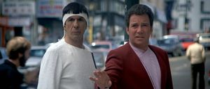Spock and Kirk are standing in front of a busy street in San Francisco in 1986. Spock looks like he is wearing a white martial arts outfit with a white headband to hide his ears. Kirk is wearing a suit that was only fashionable for a very short time in 2286.