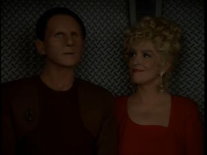 Odo and Lwaxana are standing in a turbolift. Odo is looking up at the ceiling, Lwaxana is smiling gently at him.