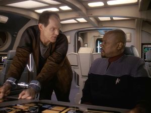 In the cockpit of a runabout, a handcuffed Eddington and Sisko eye one another warily.