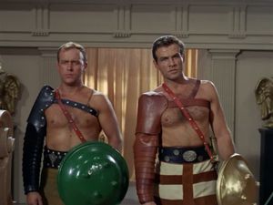 Two shirtless sixties-hot gladiators, ready for a bout,  looking slightly embarrassed about their fake-ass shields.