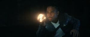 In a darkened room, a pretty young ensign holds up a small glowing orb, his eyes wide with surprise.