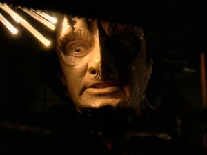 Garak is standing in the darkness in a narrow space inside a bulkhead. His face is lit by some bare optical cables. He is looking very stressed.