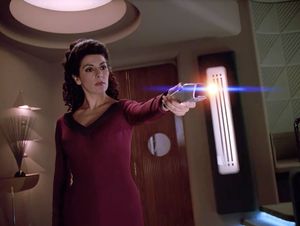 Evil possessed Deanna Troi stands in Ten Forward, firing a phaser.