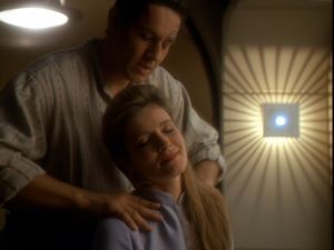 We're in a Starfleet-style cabin, with low, comfortable lighting. Janeway is sitting down, her eyes closed, with a relaxed smile on her face. She leans back as Chakotay gently massages her shoulders.
