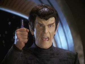 A very angry Romulan holds up a data rod. He is shouting.