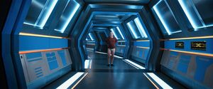 We're looking down a corridor in a starship: at the end stands a schlubby,  bearded white guy wearing a top and underpants.