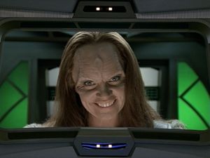 On Voyager’s main screen is an image of Seska, a young Cardassian woman with long blond hair. Her face is lit from below, and she is smiling an evil smile.