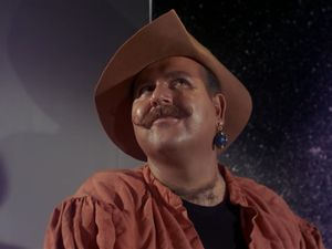 It's Harcourt Fenton Mudd, a round-faced young man with a smug expression and an impressively waxed moustache. He wears his hat with panache, and a bauble dangles from his left ear.
