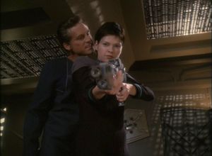 Ezri is in her quarters on DS9. We're looking up at her as she points a massive gun at us. A white guy with crap hair is standing behind her, snarling murderous suggestions into her ear.