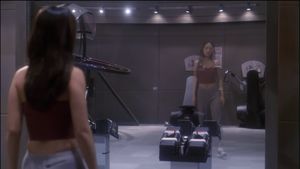 Hoshi is standing alone in the gym, wearing her exercise clothes. She looks at herself in the full-length mirror, but her reflection is transparent.